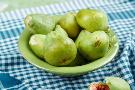 A bowl of juicy green figs and slices of fig on a blue tableclothの写真素材