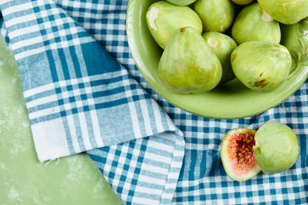 A bowl of juicy green figs and slices of fig on a blue tableclothの写真素材