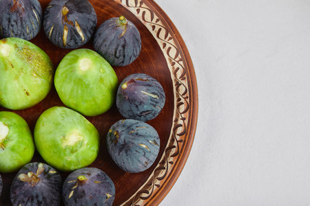 Purple and green figs in a pottery plate
