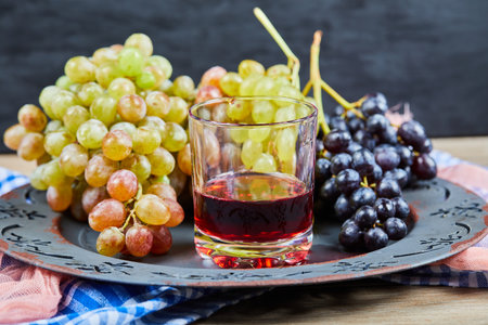 A cup of wine with grape bunches aroundの写真素材