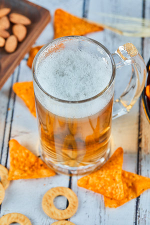 A glass of beer and chips on blue table, close upの写真素材