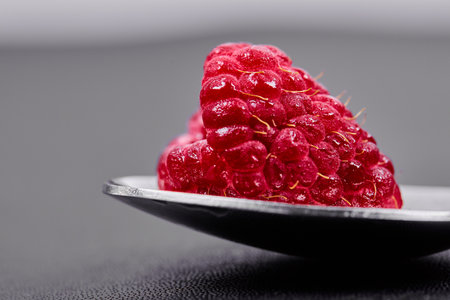Single large raspberry on spoon. Close up