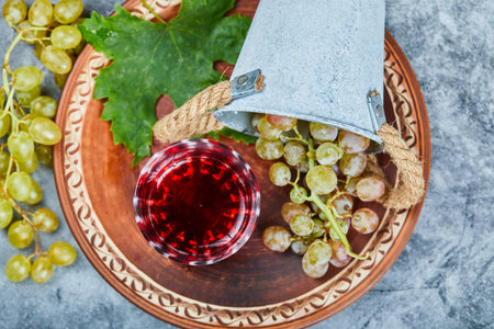 A glass of red wine with a bunch of green grapes aroundの写真素材
