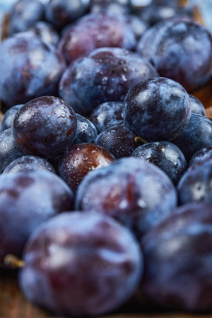 Garden plums in a wooden plate, close upの写真素材