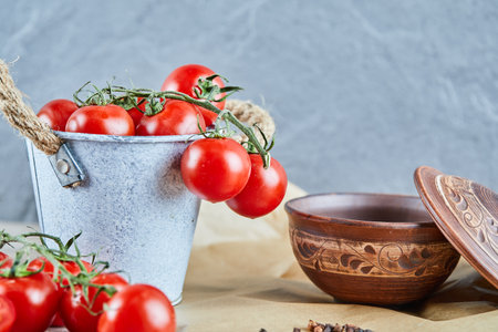 Bucket of tomatoes and empty bowl on blue backgroundの写真素材