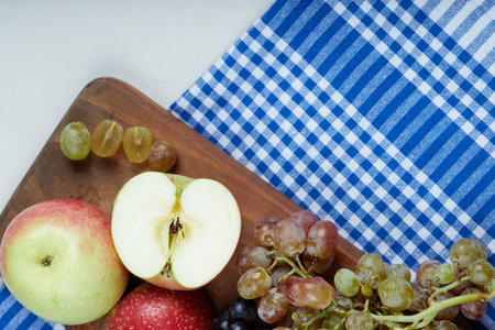 Red green apples and grape bunches on a wooden boardの写真素材