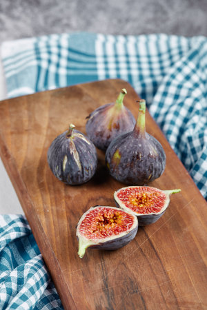 Half slices and whole figs on a wooden board with a blue tableclothの写真素材