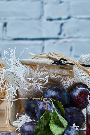 Garden plums in a basket on a blue backgroundの写真素材