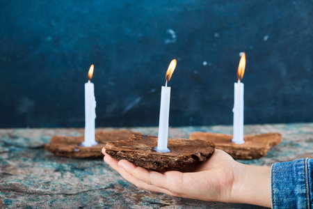 Woman holding burning candles on marble tableの写真素材