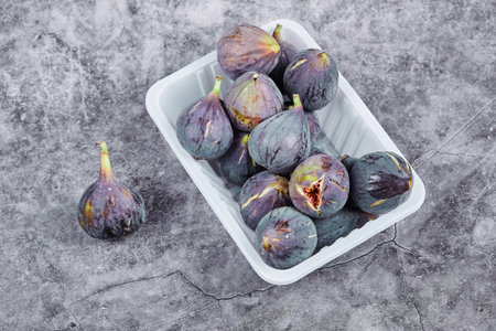 Purple figs in a white plastic containerの写真素材