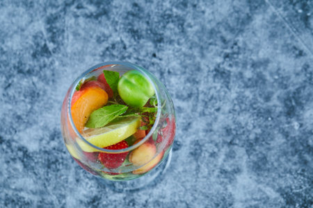 A glass of juice with whole fruits inside on blue backgroundの写真素材