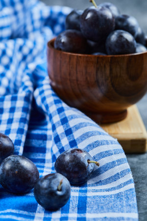 Garden plums in a bowl on a marble background with tableclothの写真素材