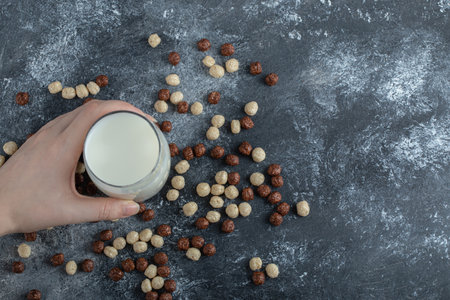 Female hand holding glass of milk on marble surfaceの写真素材