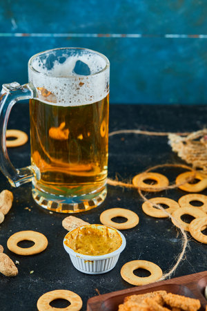 Crackers and a glass of beer on dark backgroundの写真素材