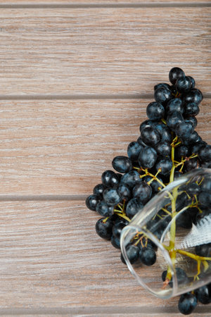 A wine glass with a bunch of red grapes on the tableの写真素材