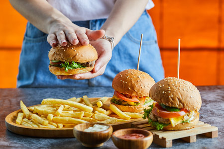 A woman hand holding cheeseburger with fry potato, ketchup, mayonnaiseの写真素材