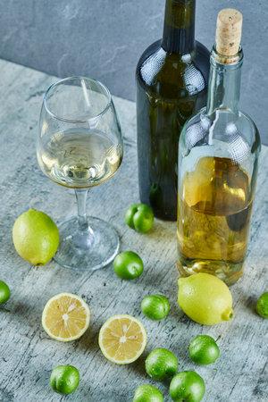 Two bottles and glass of wine on marble table with lemons and cherry plumsの写真素材