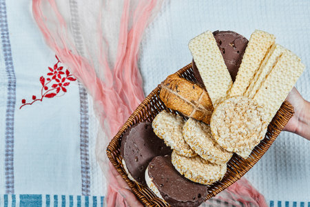 Hand holding a basket of mixed biscuits on a tablecloth