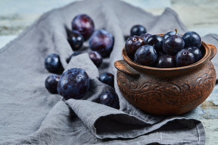 Garden plums in a bowl on gray tableclothの写真素材