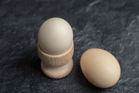 Egg cup and Two raw egg on black backgroundの写真素材