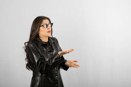 Image of a young woman in black coat wearing glasses and posing