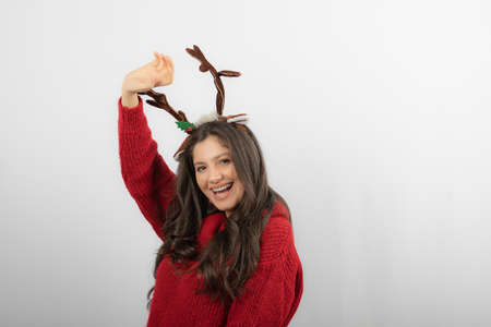 Smiling girl wearing a Christmas sweater and adorable deer horns headbandの写真素材