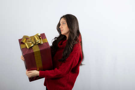 Beautiful girl holding a Christmas present and looking away
