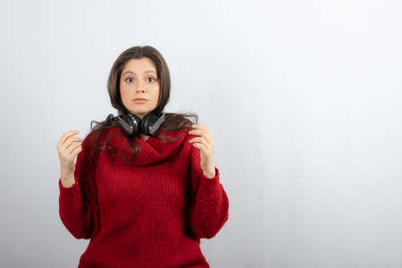 Photo of a young woman in red sweater wearing headphones on neckの写真素材