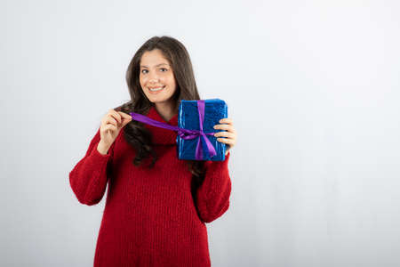 Portrait of a smiling woman opening a Christmas gift box with purple ribbonの写真素材