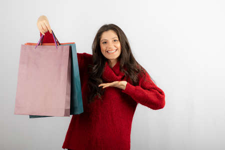 Photo of a smiling lady pointing at colorful shopping bagsの写真素材