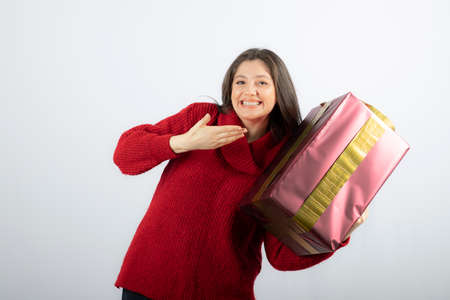 A young woman showing at a Christmas gift boxの写真素材