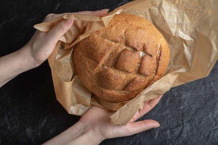 Woman unwrap freshly baked rye bread with her hands