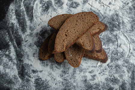Top view of sliced brown bread on flour background