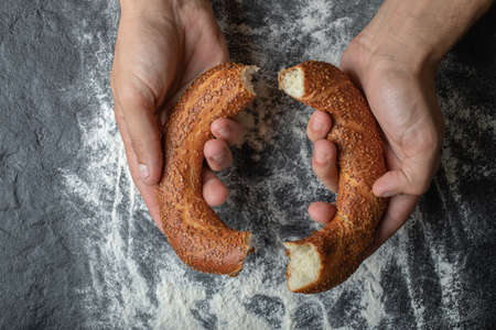 Woman cutting delicious Turkish simit with hands
