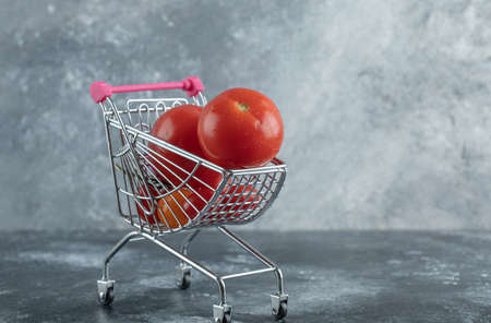 Fresh red tomatoes in small shopping cartの写真素材