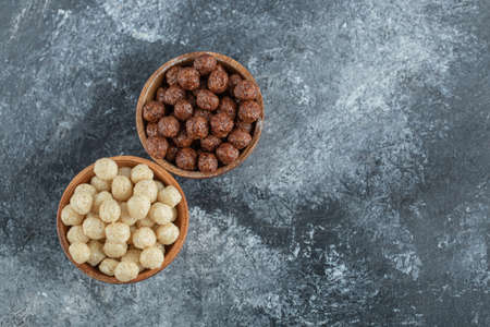 Wooden bowls with sweet corn balls on a gray background