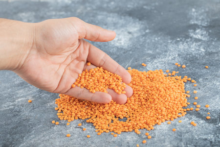 Man hand taking a heap of raw lentils