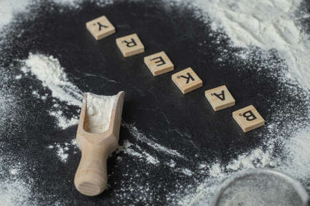 A wooden spoon with flour and wooden letters