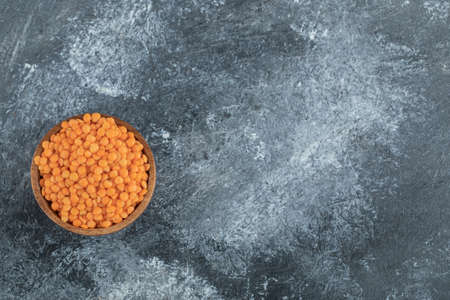 A wooden bowl full of raw lentils on a gray backgroundの写真素材