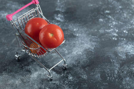 Fresh red tomatoes in small shopping cartの写真素材