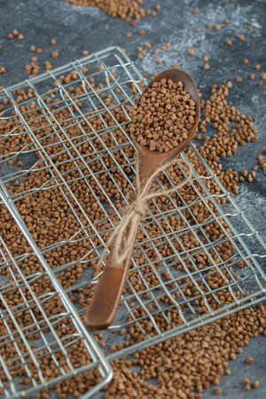 Wooden spoon full of raw buckwheat on marble surfaceの写真素材