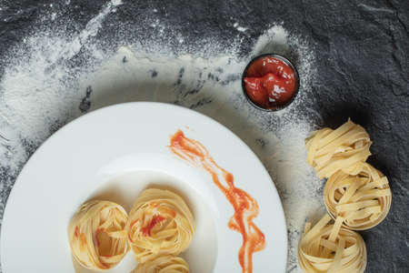 A white plate of uncooked nest noodles with red pepperの写真素材