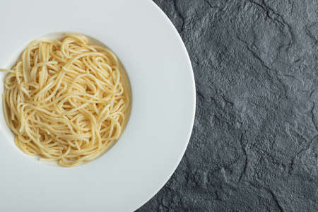 Delicious noodles in a white plate on a dark background