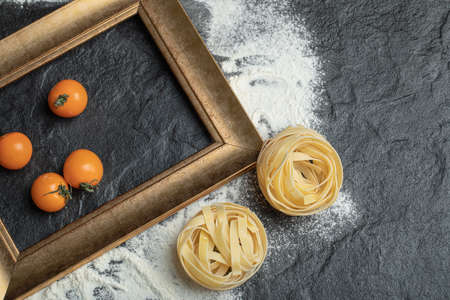 Raw nest pasta with flour and cherry tomatoesの写真素材