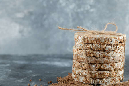Delicious crispbread and raw buckwheat on marble background