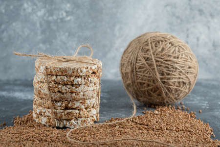 Delicious crispbread, yarn and raw buckwheat on marble background