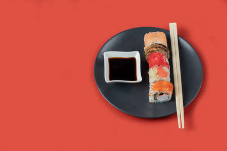 Sushi set with sauces in a black platter on red backgroundの写真素材