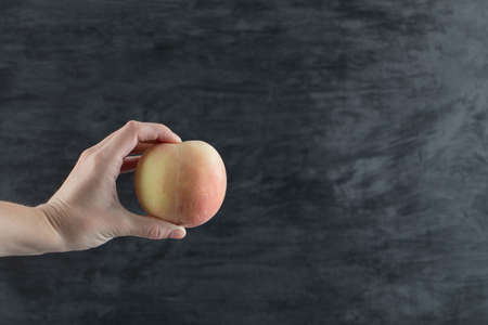 Farmer holding a yellowish redish apple between fingers