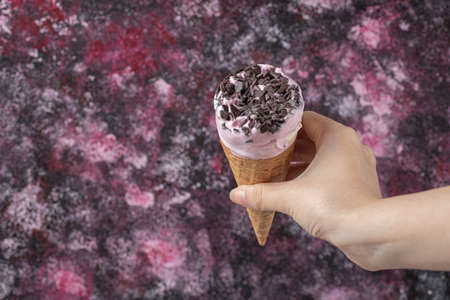 Holding a blueberry icecream in waffle cone
