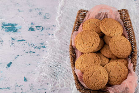 Oatmeal cookies in a wooden basket on a pink kitchen towel